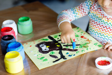 Closeup of little creative toddler girl painting with finger colors an owl bird. Child having fun with drawing at home, in kindergarten or preschool daycare. Games, education and distance learning for