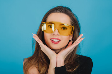 beautiful sporty girl dressed in black bodysuit with yellow glasses on blue background