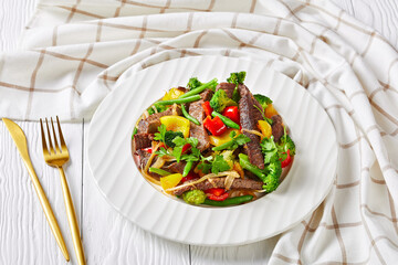 Vegetables with sliced beef steak on a white plate