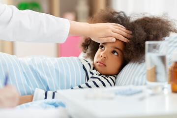 Fototapeta premium healthcare, medicine and people concept - doctor with clipboard and little sick african american girl lying in bed at home