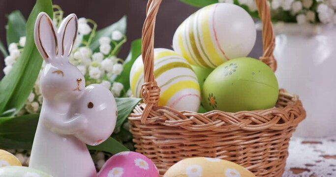 Easter concept. Easter bunny, white lilies in a vase and eggs in a basket. 4K
