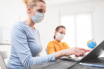 Obraz premium Child home studying education, homeschooling, with private tutor / mother with protective mask in the time of viruses, flu and seasonal pandemic, healthy approach in social contact.