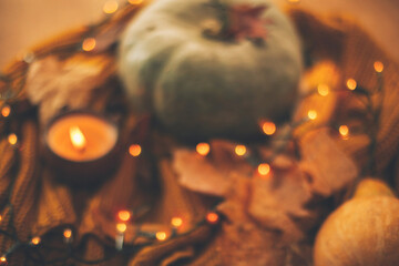 Autumn abstract background. Blurred image of pumpkin, autumn leaves, candle, warm lights on yellow...