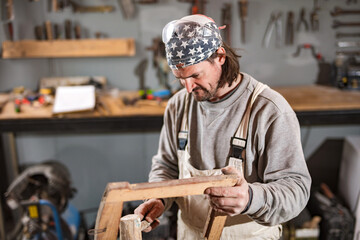 Male carpenter working on old wood in a retro vintage workshop.