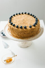 Homemade honey cake with milk cream and blueberries.