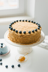 Homemade honey cake with milk cream and blueberries.