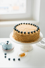 Homemade honey cake with milk cream and blueberries.