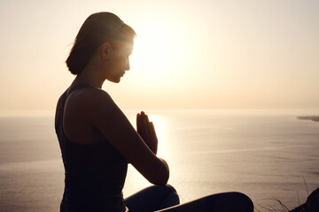Young woman practicing yoga over sunset sea