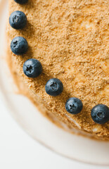 Homemade honey cake with milk cream and blueberries.