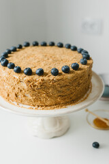 Homemade honey cake with milk cream and blueberries.