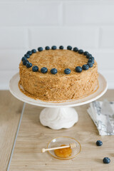 Homemade honey cake with milk cream and blueberries.