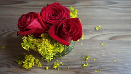 red roses with yellow flowers in a vase , on a wooden background