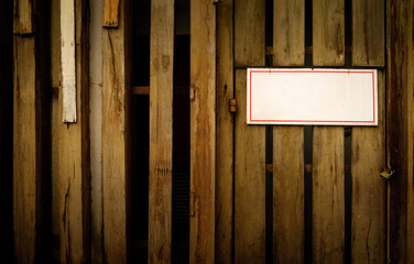 The rough texture wooden fence attached with a white blank sign