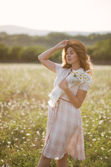 Fototapeta na wymiar Young beautiful woman relaxing in chamomile field.