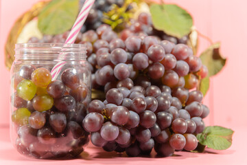 Pot with grains and grape bunches on pink background