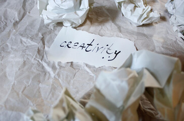 Hand written word "creativity" on piece of paper on crumpled paper background