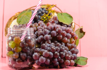 Pot with grains and grape bunches on pink background