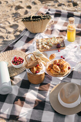 Beautiful cozy summer picnic with lemonade, fresh bread and fruits on a beach.