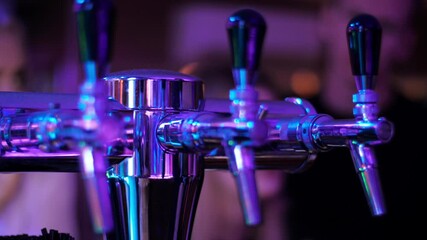 Equipment for production, bottling and cooling the beer and other beverages in bar or restaurant. Beer tap on colorful night party. Multi-colored lights of party