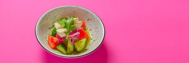 Healthy organic vegan vegetable salad served in a bowl over bright pink background. Spring seasonal concept.