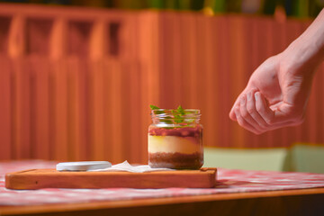 A jar of sweet and delicious dessert with caramel and peanut butter. Salty dessert. Peanuts. Served on a wooden board.
