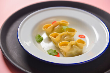 Close up fresh boiled dumplings with hot steams on white ceramic plate. Chinese food, Asian cuisine.