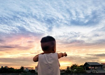 Fototapeta premium Baby boy standing in front of the sunset