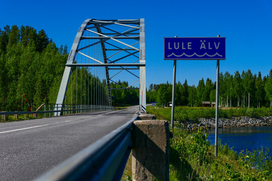 Jokkmokk, Sweden The Lule River On A Sunny Day And Bridge.