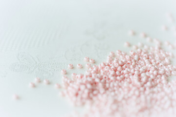 Pink seed beads scattered on the textile background close up. Handmade concept