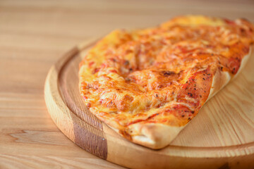 Calzone, Italian traditional food. Served on wooden board over rustic wooden table background closeup.