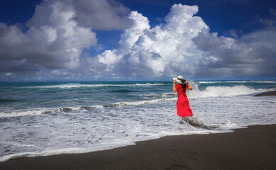 Woman standing on black sand beach in Padangbai, Bali Island, Indonesia.