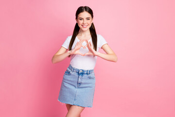 Obraz na płótnie Canvas Photo of pretty nice lady holding arms in heart figure good mood express cardiac feelings wear casual white t-shirt mini jeans skirt isolated pastel pink color background