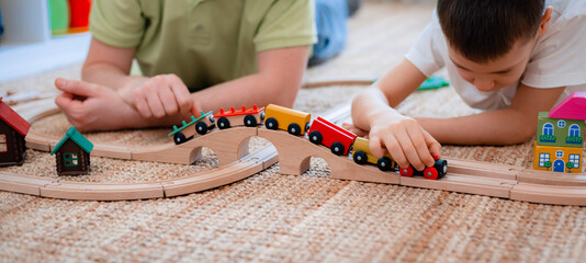 family father and son play a toy wooden railway in the game room. The concept of a parent and child...