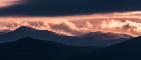 Dramatic winter storm blows over a cold barren landscape near sunset
