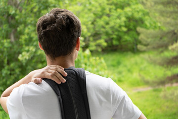 Young man with spine and back pain wears orthopedic and support corset