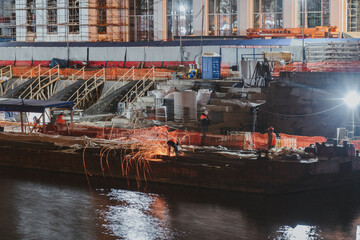 Construction site at night with workers who weld