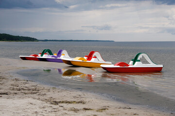 Four bright multi-colored catamarans moored to the shore. Riga seaside (Baltic Sea) before a thunderstorm.
