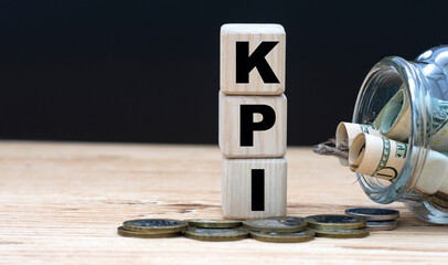 KPI - abbreviation on cubes on the background of a capacity with money