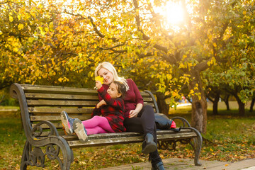 mother and daughter on a bench in autumn park