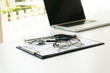 Close-up of stethoscope, paper, laptop on doctor table.