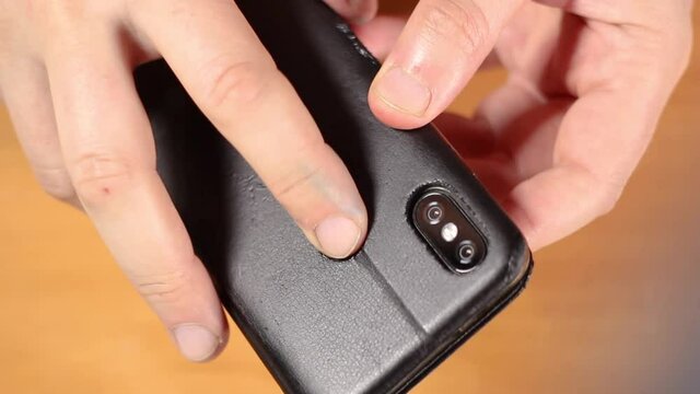 male hold twists in hands a smartphone in a black case