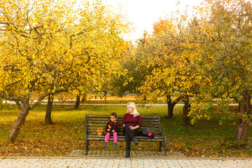 Fototapeta premium Happy mother and daughter embracing on a bench in an autumn park