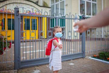 New normal back to school. Father passing her daughter in medical mask a sanitizer. Stay safe