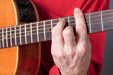 Fingers of a guitar player playing acoustic guitar.