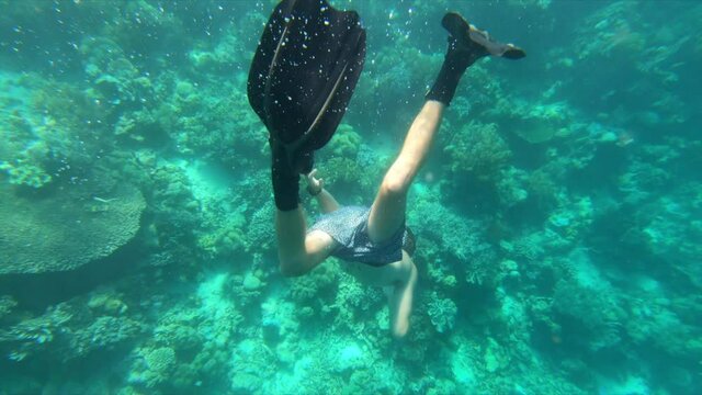 Slow motion shot of shirtless young man snorkeling over coral reef in sea - Wakatobi Regency, Indonesia