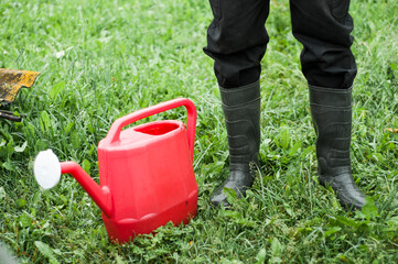 ubber boots with watering can on grass - spring concept