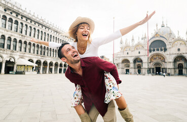 Beautiful couple in love having fun embracing and laughing doing piggyback ride at holiday in...
