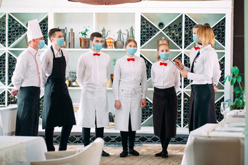 Employees of a Restaurant or Hotel in protective masks. End Of Quarantine. Restaurant Manager and his staff on the terrace. interaction with the chef in the restaurant.