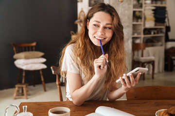 Beautiful young smiling girl sitting at the kitchen table