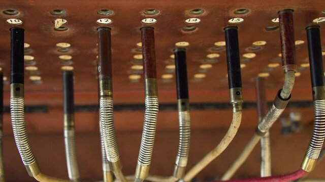 Hand plugging an audio jack into copper wall, old telecommunication machine